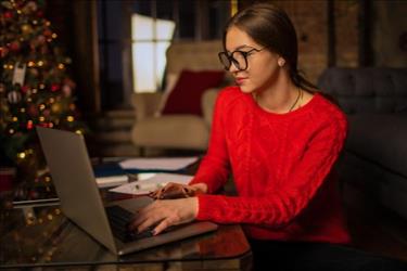 woman on computer with christmas tree in background