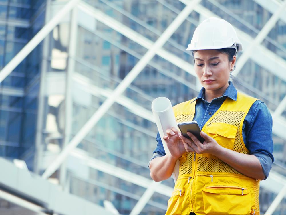 construction project manager checking her phone on a work site