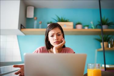 concerned job seeker looking at postings on her laptop
