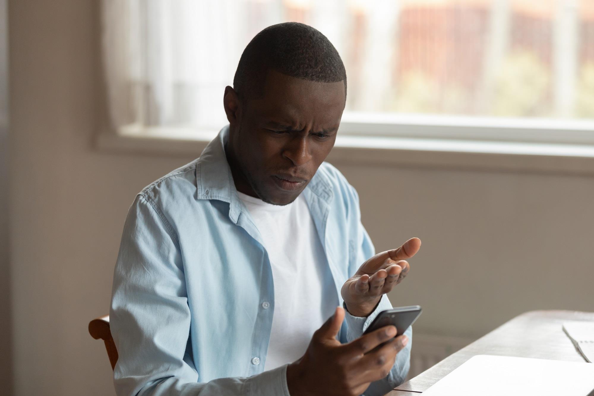 job seeker annoyed by the job postings he's reading on his phone