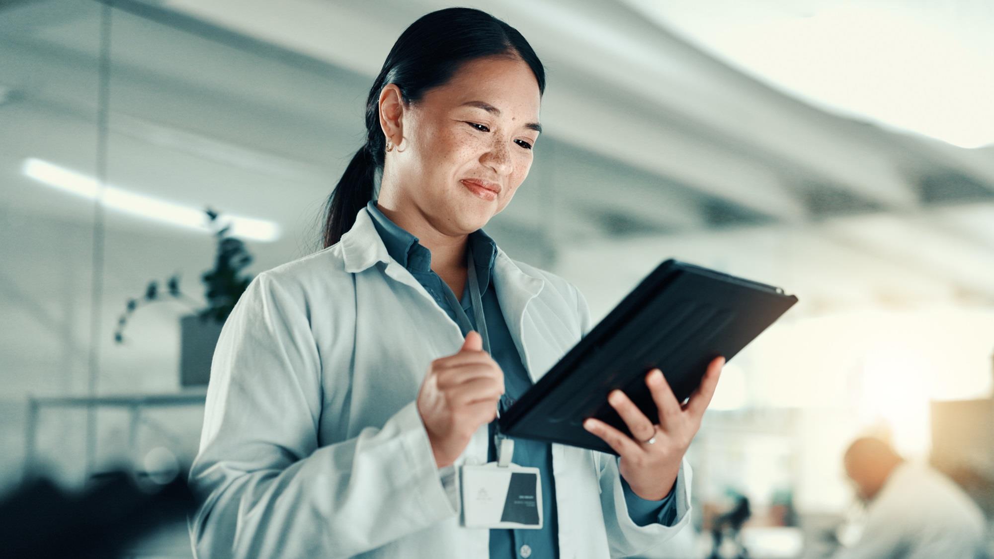 medical team member smiling while looking at her tablet