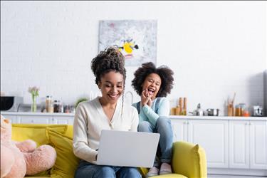 happy mother working at home with her child behind her