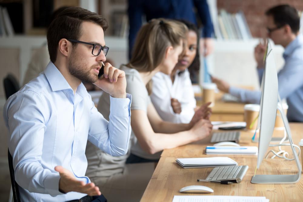 Easily irritated office worker getting frustrated while sitting at his desk