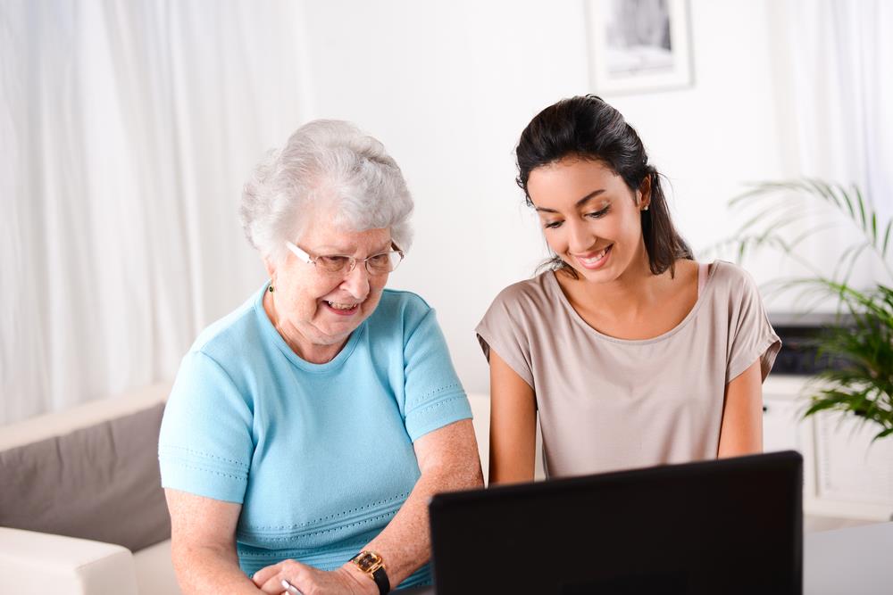 female social worker helping elderly woman use computer