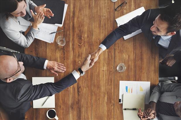 People shaking hands across table at business event