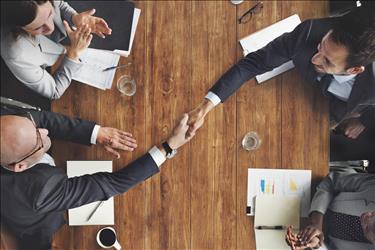 People shaking hands across table at business event