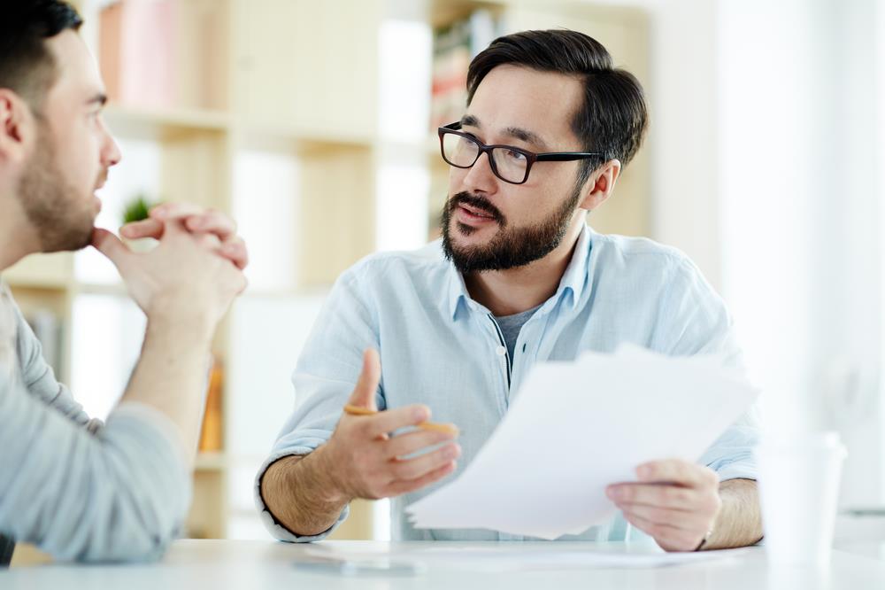 Boss with paper asking his employee a question