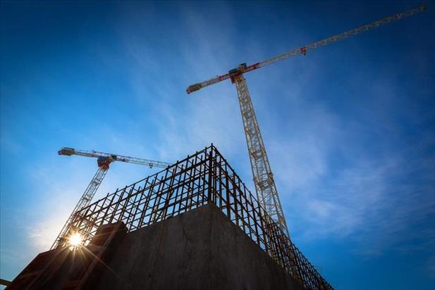 Ground view of commercial construction site with crane against a blue sky