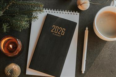 2026 planner on a desk with holiday decorations around it and a coffee mug