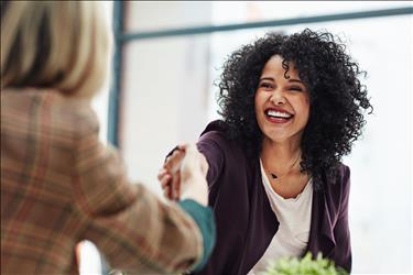 smiling job seeker shaking hands with her interviewer