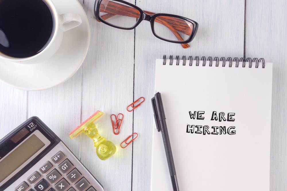 optometry practice manager's desk with notepad that reads, "we are hiring"