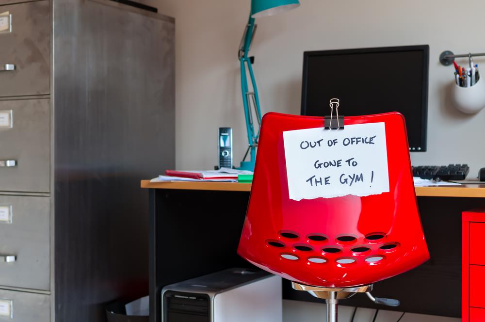 employee's desk chair with "out of office gone to the gym" message on the back