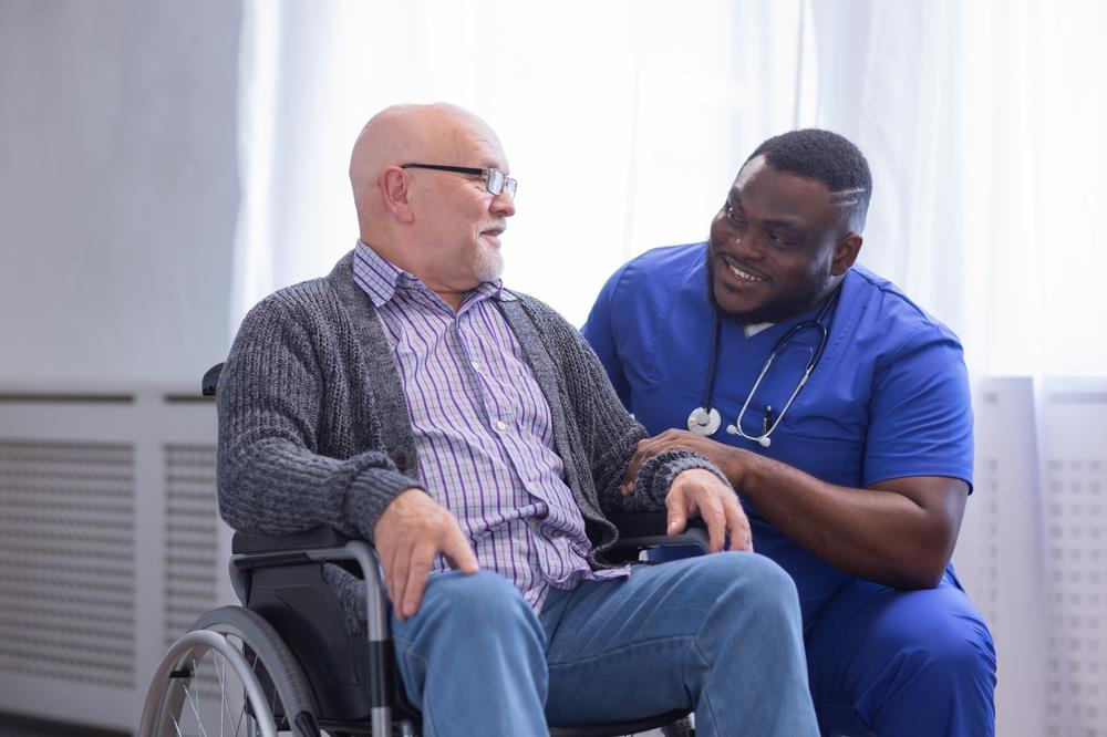 smiling nurse assisting his patient in a wheelchair