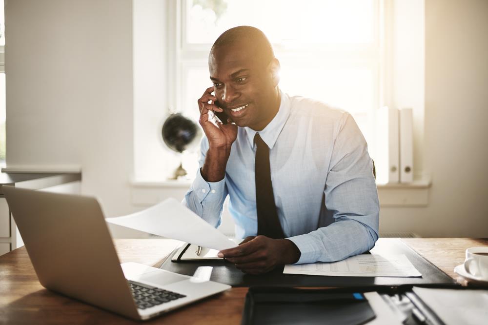 accountant on the phone reviewing data on his laptop