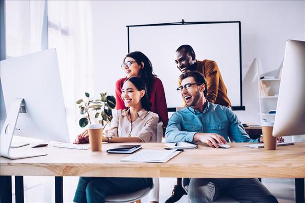 group of employees gathered at a computer smiling at the screen