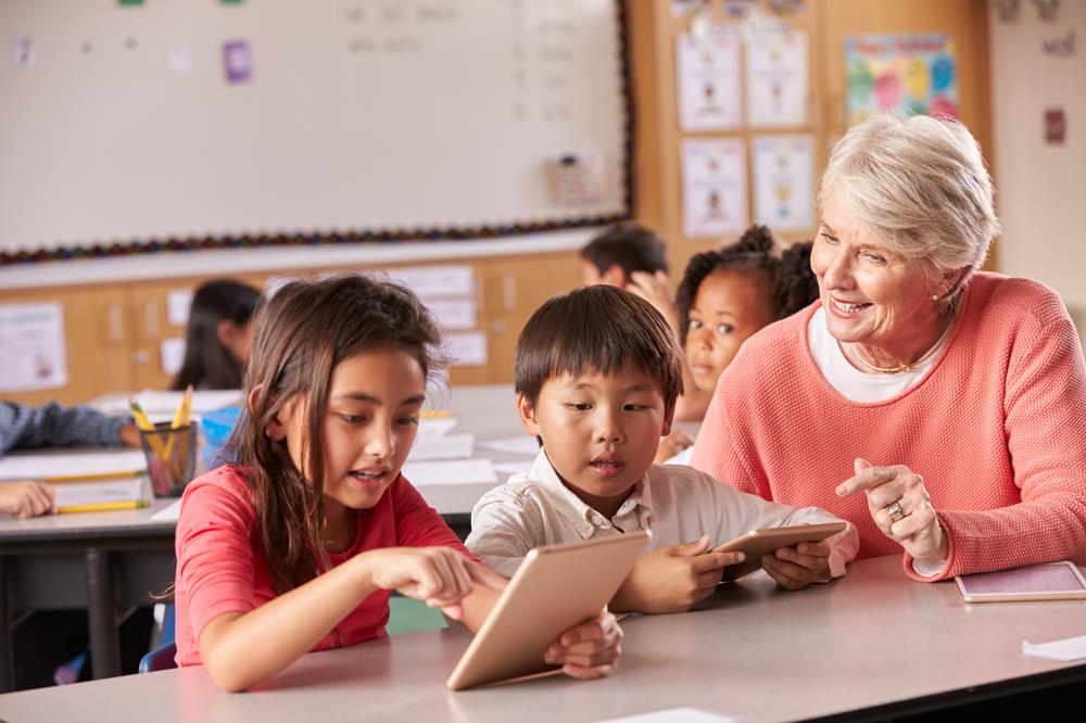 school principal working with elementary students in the classroom