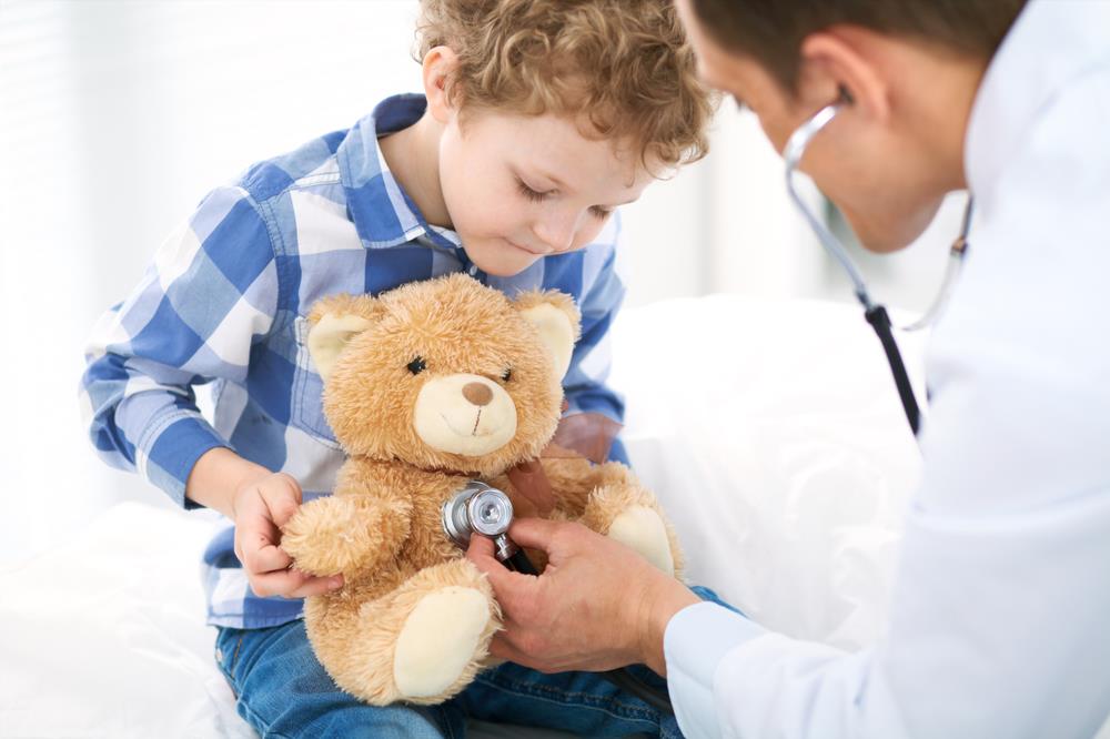 pediatrician pretending to check the heartbeat of her patient's teddy bear