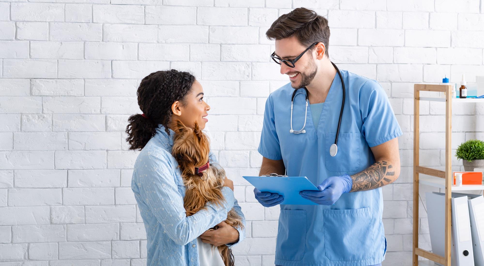 veterinarian talking to a client while she holds her dog