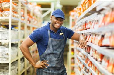 Hardware store employee smiling next to merchandise