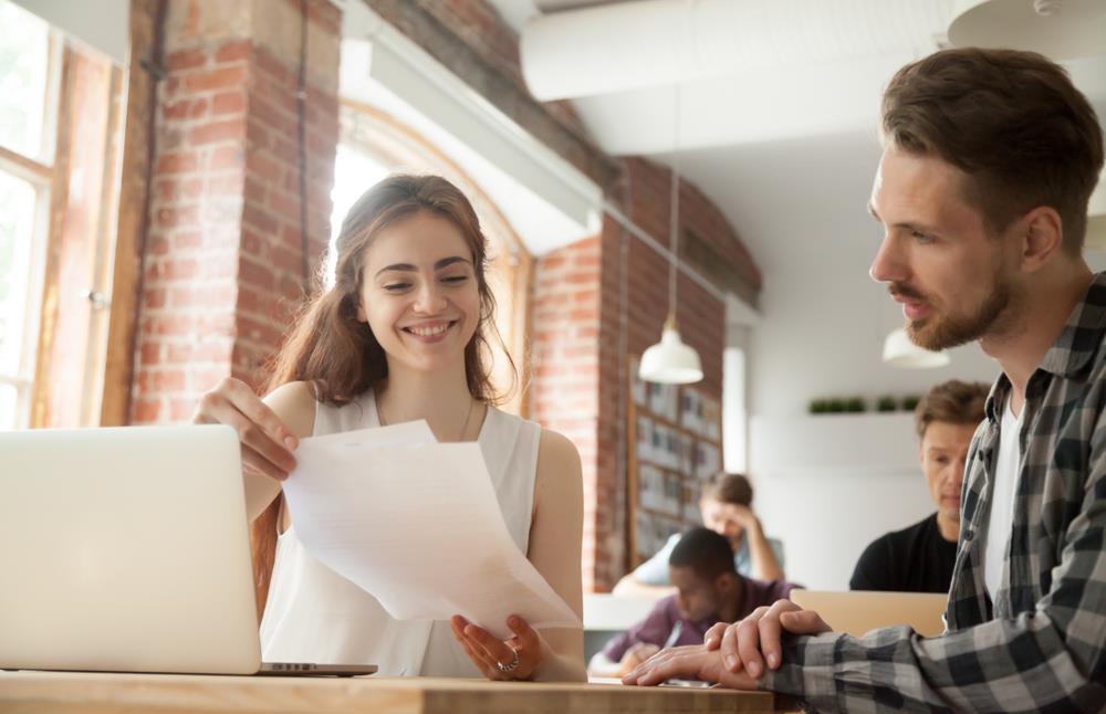 Woman showing coworker paper