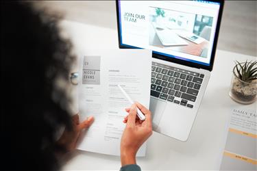 person reviewing a resume with their laptop open to a career site