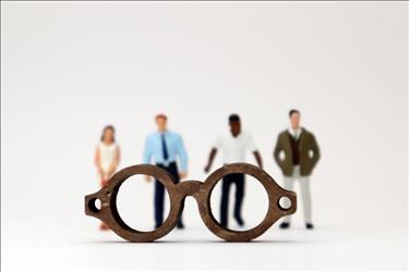 a pair of glasses in front of four job candidates