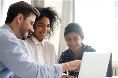 Man teaching smiling interns something new on the computer