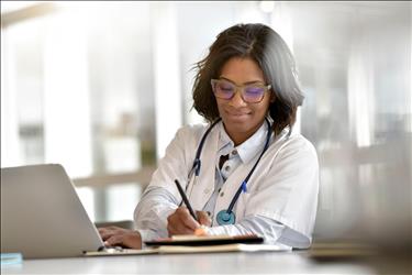 doctor using her laptop and taking notes