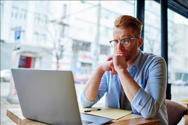 serious freelancer looking at his laptop in a cafe