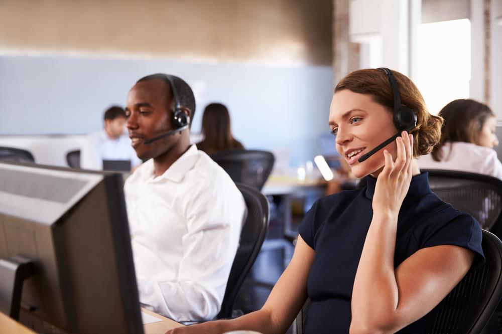 two customer service representatives on their phones at their desks