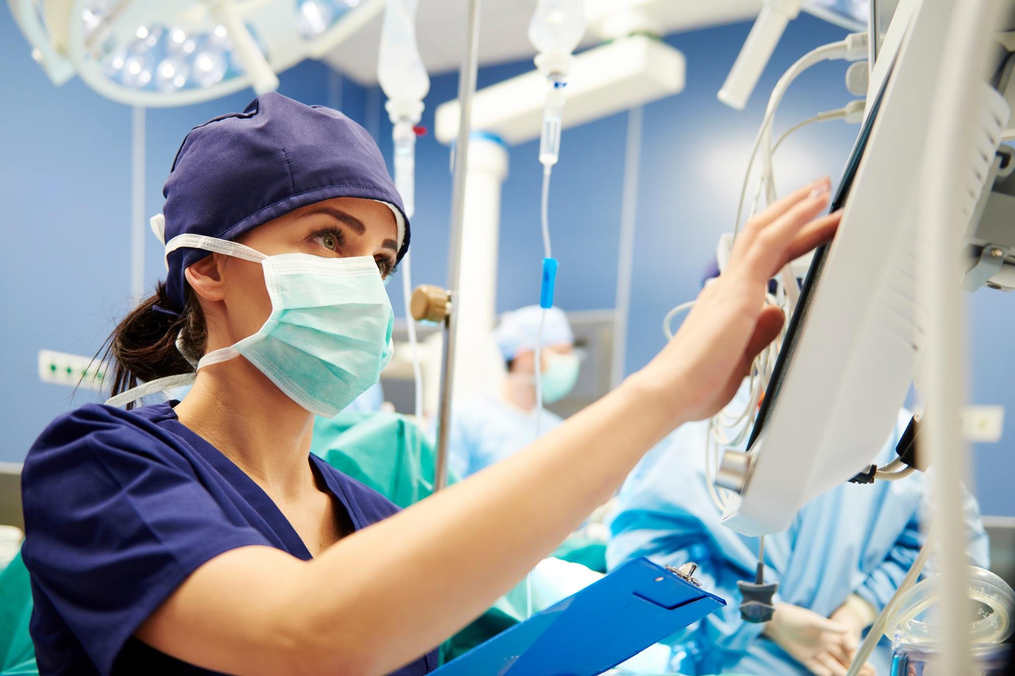 nurse checking data on a computer in a surgery room
