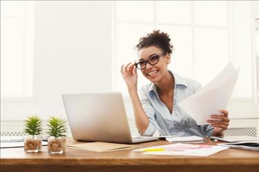 woman looking at computer with glasses and a piece of paper