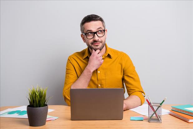 person thinking while working on their laptop