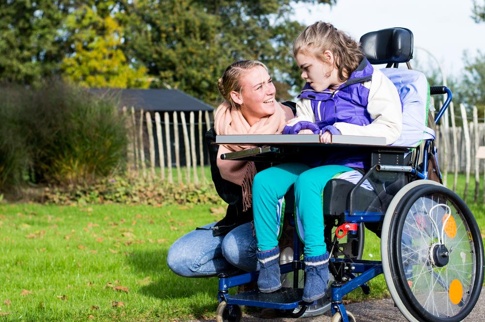 caregiving professional helping a young girl with a disability