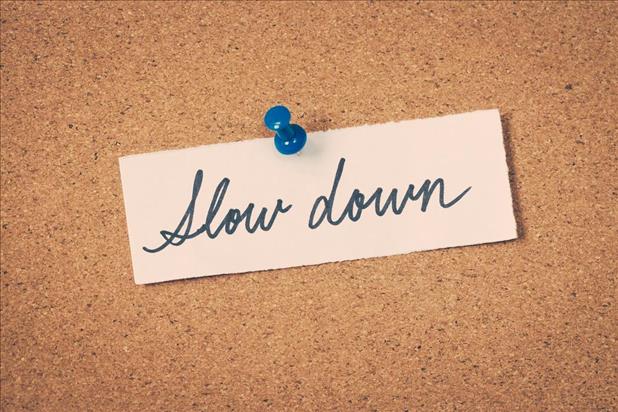 bulletin board with note pinned on it saying "slow down"