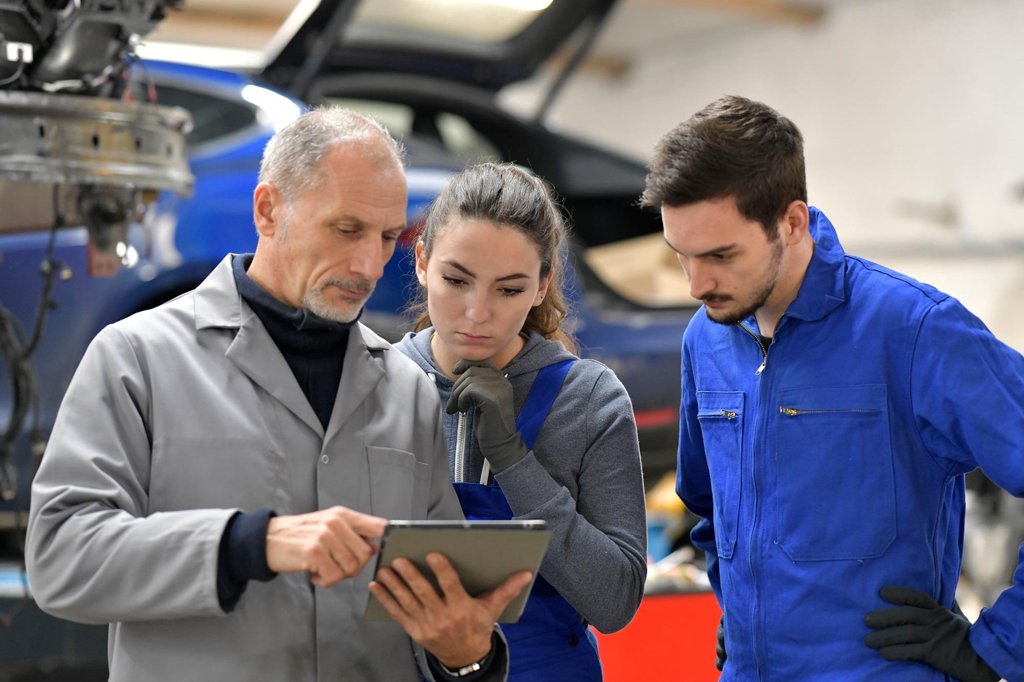 auto mechanic instructor with two apprentices