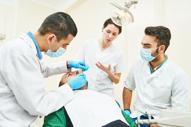 Allied dental educator overseeing patient examination