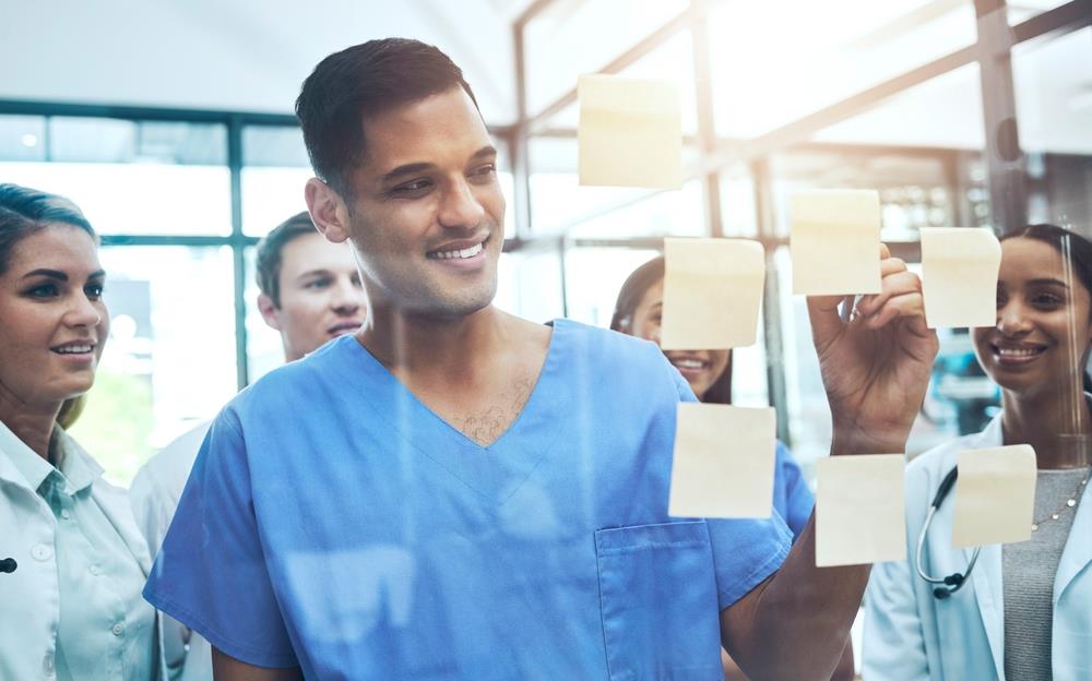 healthcare team putting notes together on a glass board