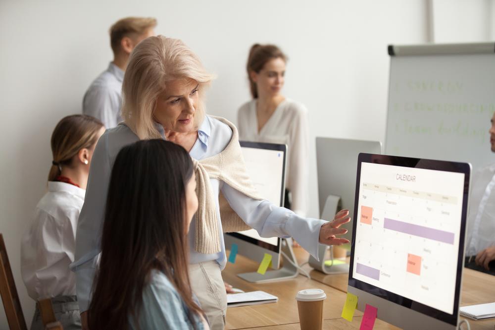 Boss showing her new employee something on the computer