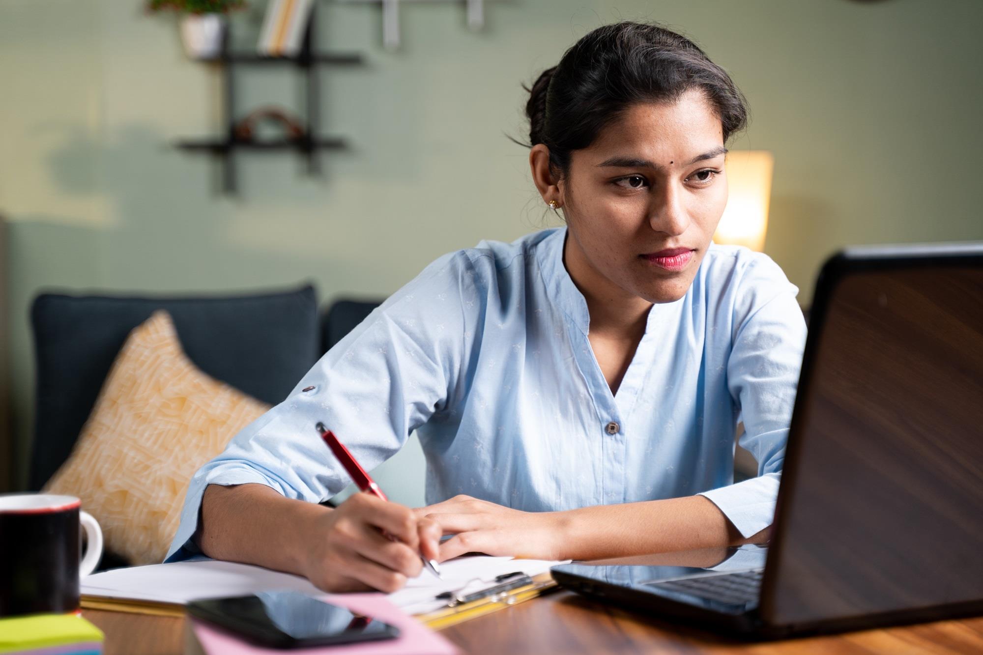 employee taking notes while looking at her laptop