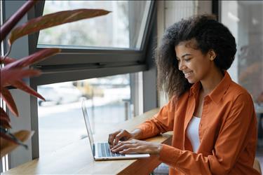 happy employee working on her laptop by a window