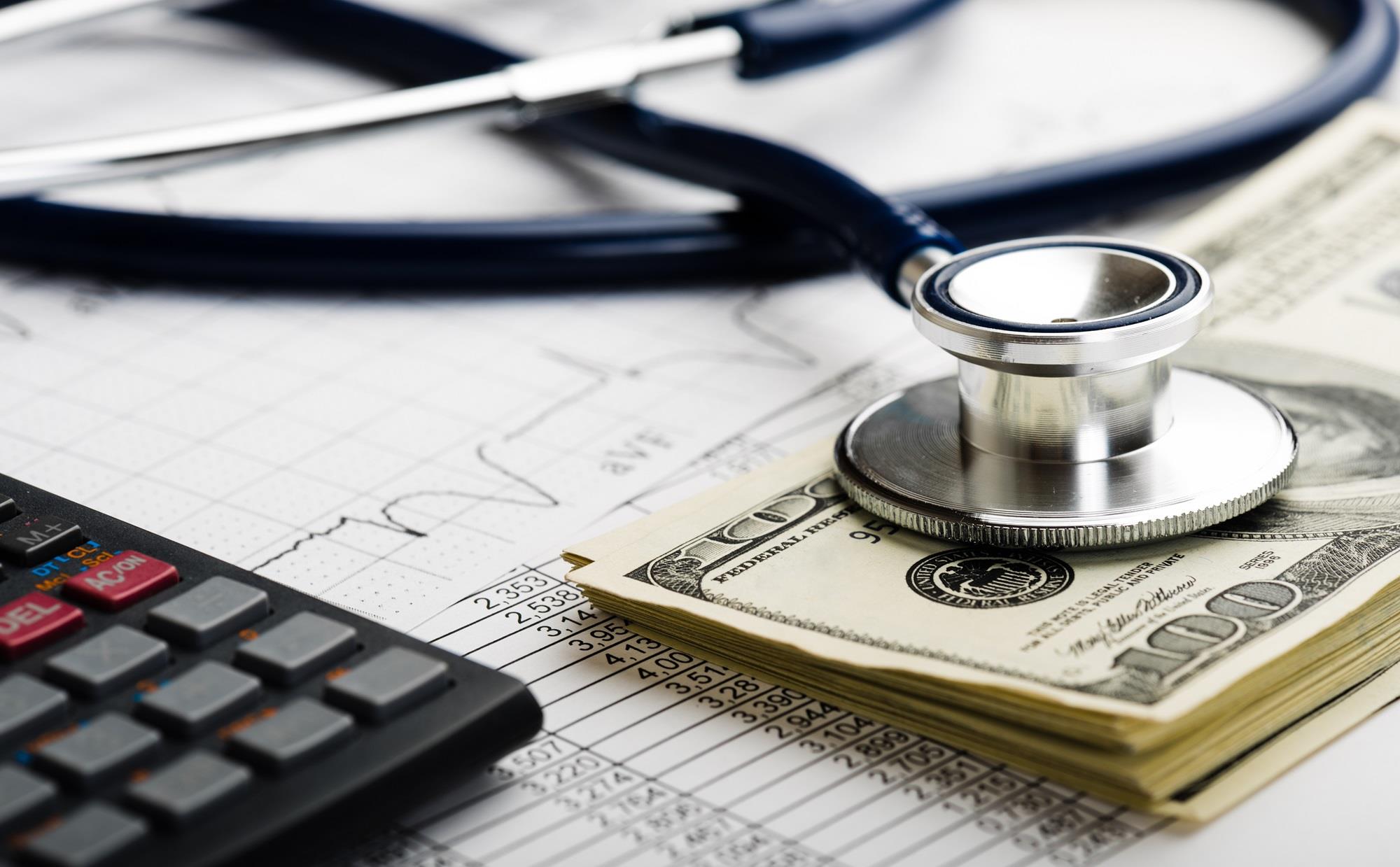 a calculator, money, charts, and stethoscope on a table