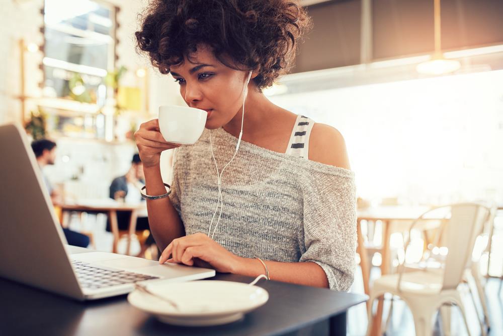 female marketing professional taking an online course on her laptop in a cafe