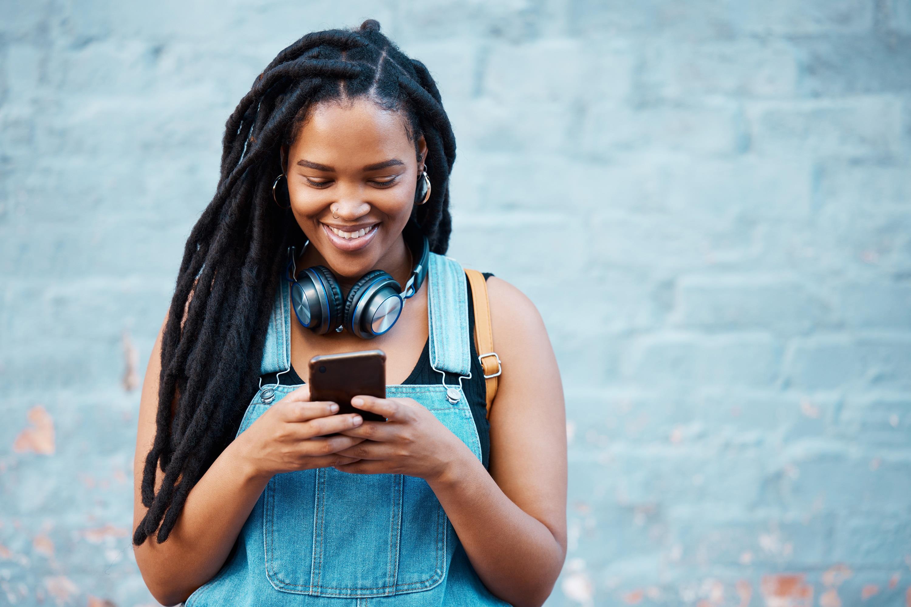 young african american woman smiling while looking at her phone